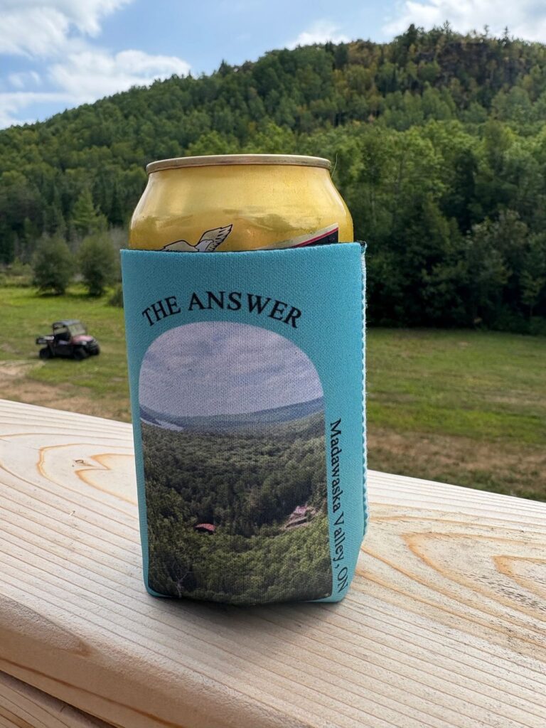 A can in a blue koozie with a scenic mountain view in the background.