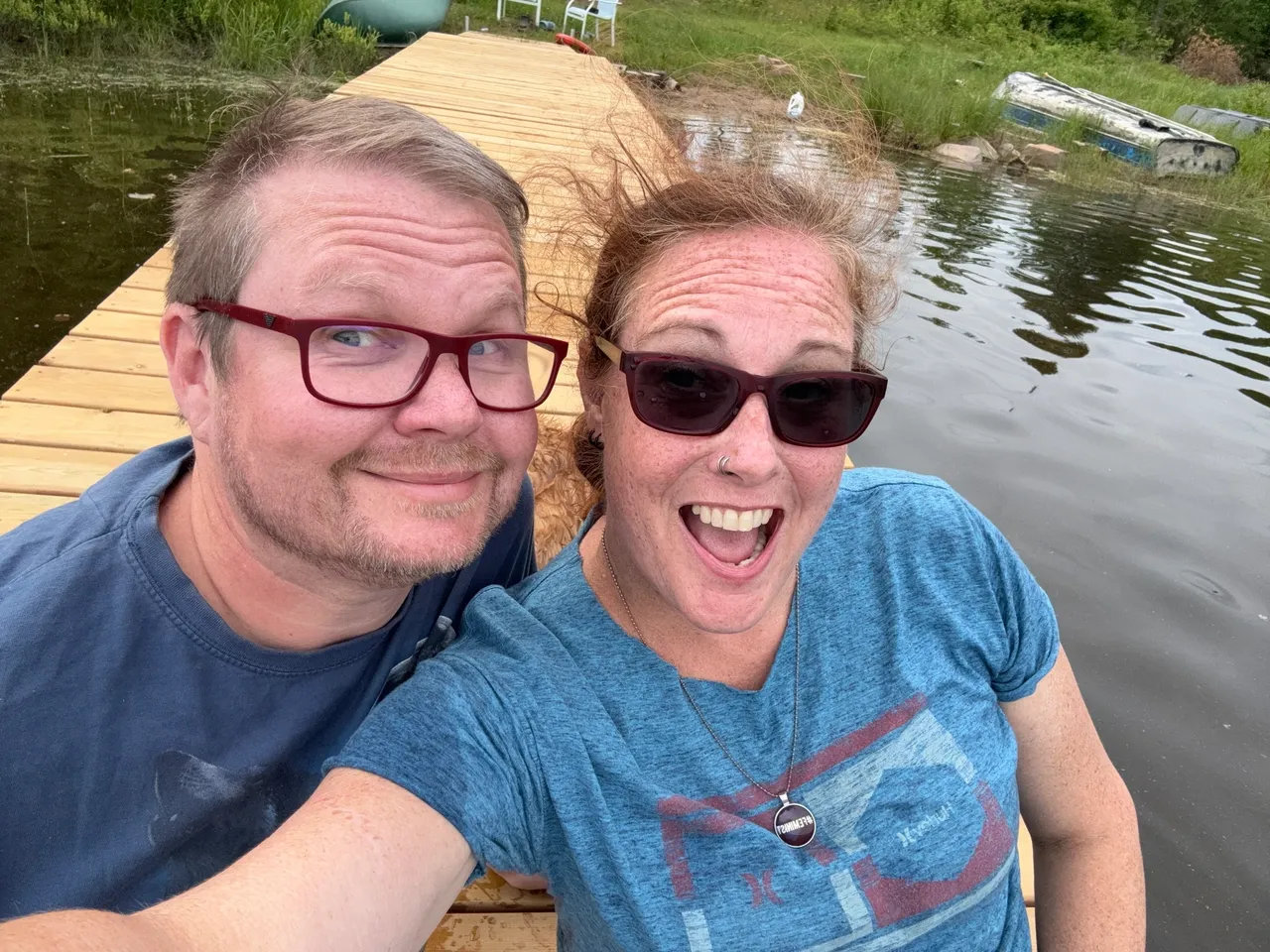 A cheerful couple enjoys a selfie by the water on a sunny day.