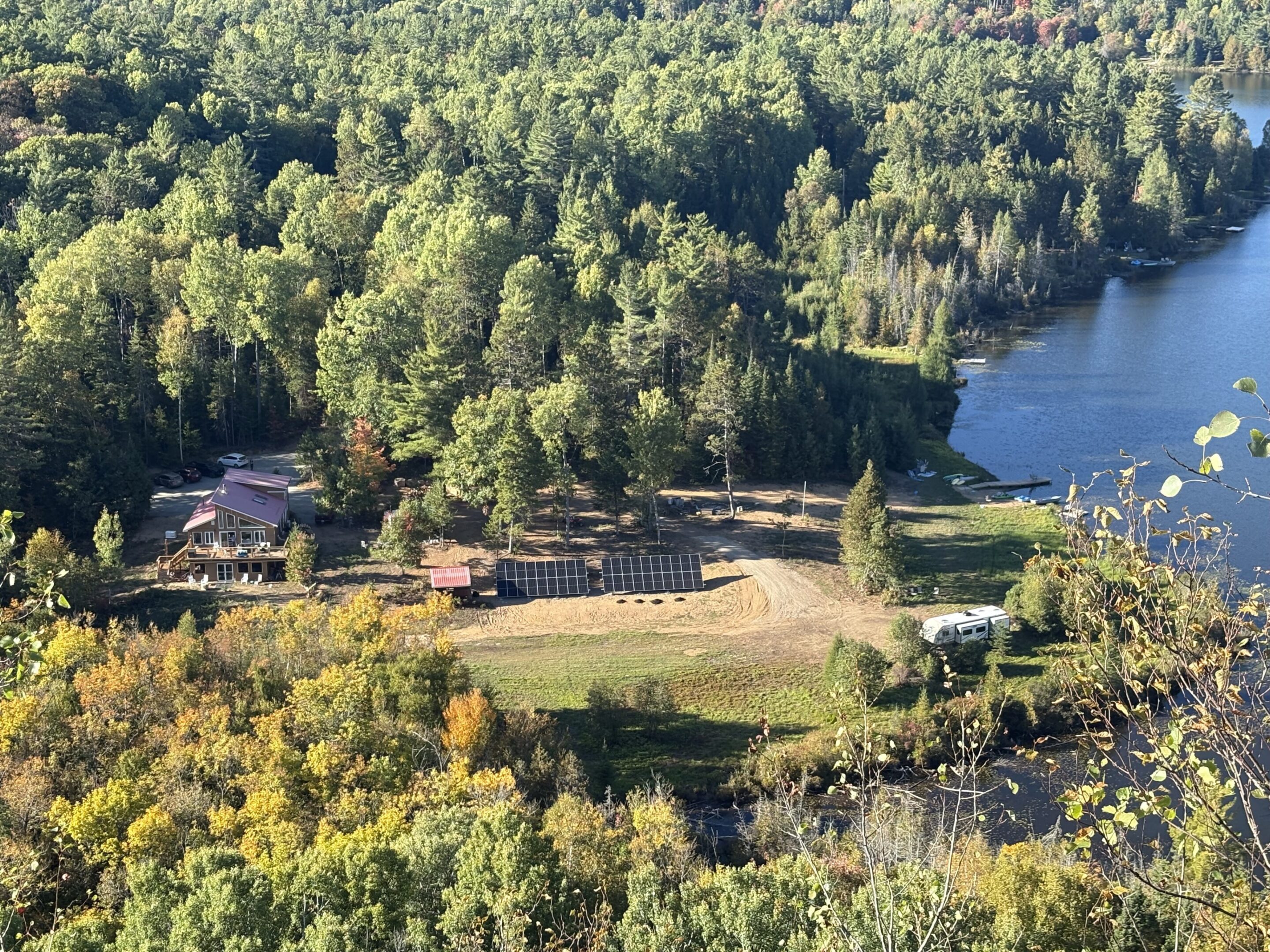 A scenic forested lakeside with scattered buildings and a clear shoreline.